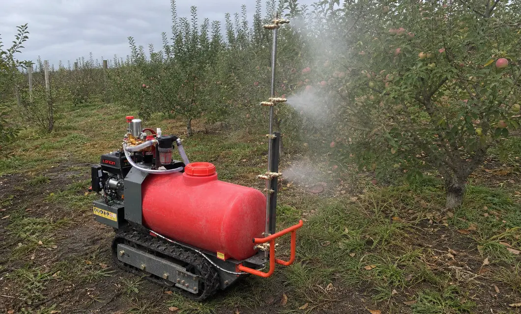 Lo spruzzatore cingolato copre le file del frutteto di mele con nebbia verticale.