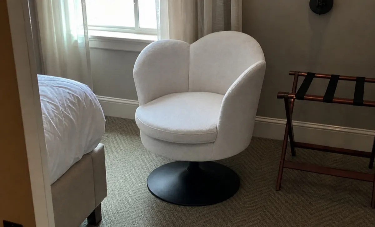 Cushioned lounge seat beside vanity storage for bedroom dressing.