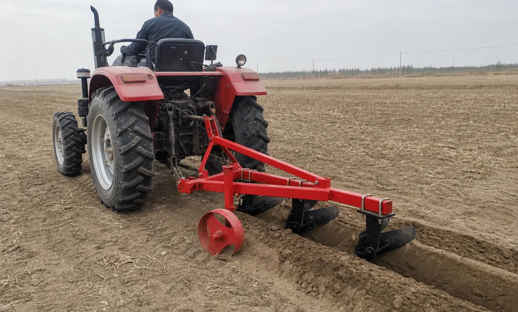 La escena de tierra seca muestra tres cuchillas de arado formando lomos detrás de un tractor.