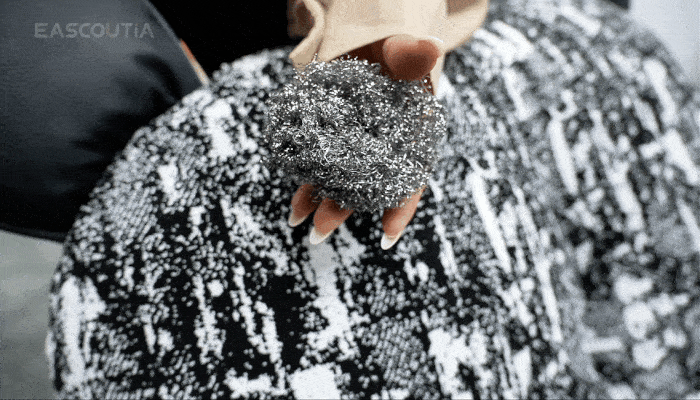 Repeated steel-wool rubbing leaves the patterned fabric texture and appearance intact, visibly demonstrating scratch resistance.