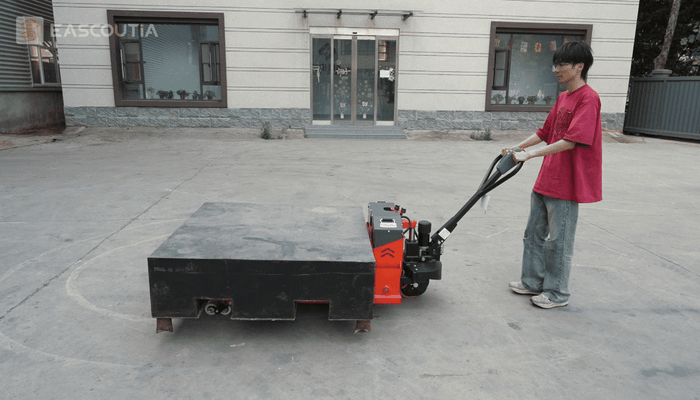 Powered travel moves the forks and material together, with travel controls grouped at the handle.